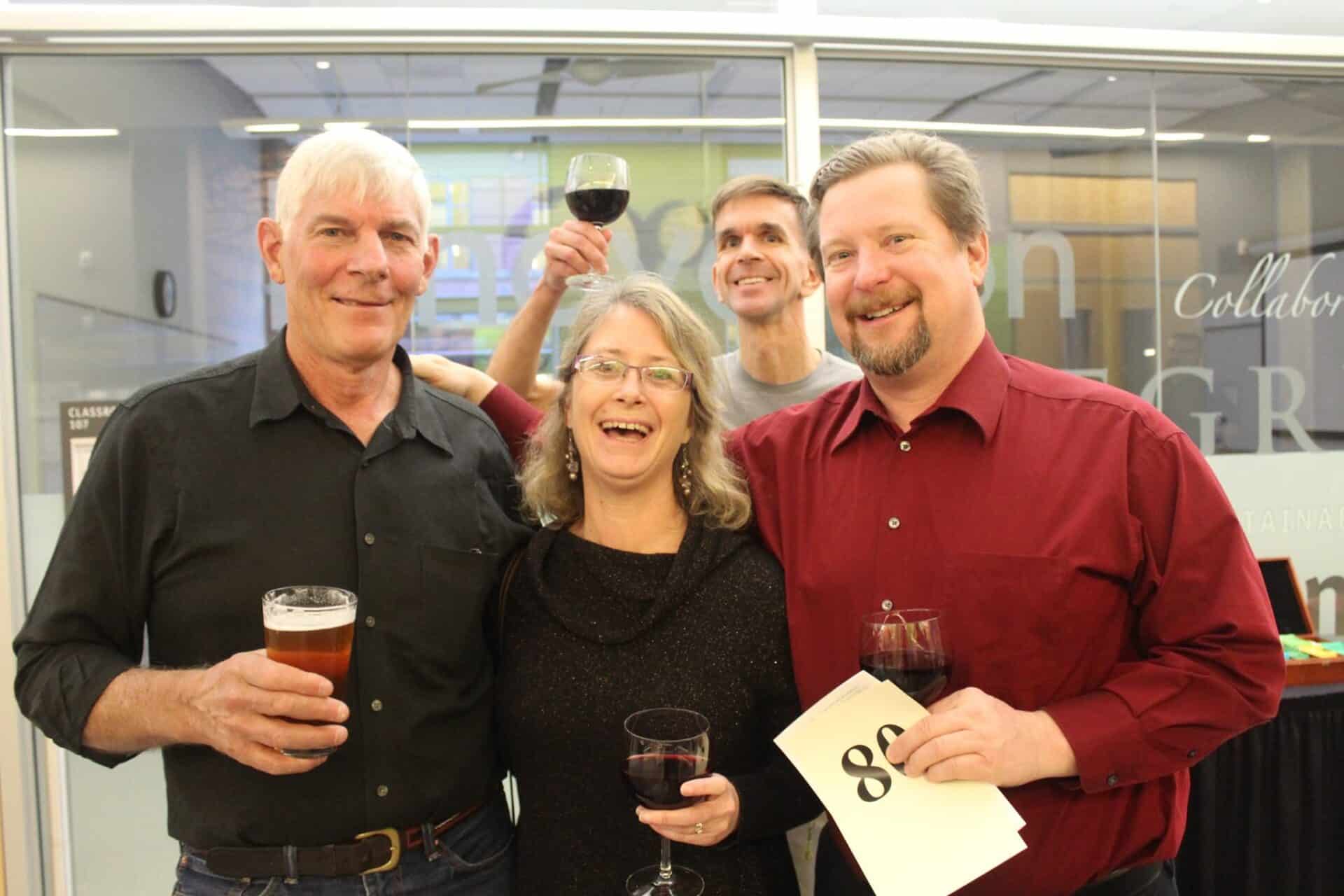 Four friends toast and smile for the camera.