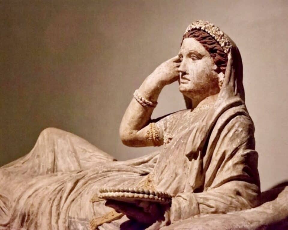 An Etruscan terracotta sarcophagus lid depicting one Larthia Seianti. 2nd century BCE. The woman has her right hand up to her face and is lying recumbant looking to her left.