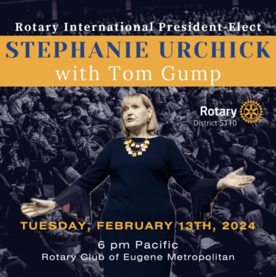 Stephanie Urchick addresses a crowd with outstretched hands. She has shoulder-length blond hair. She's wearing a black dress with a statement necklace.