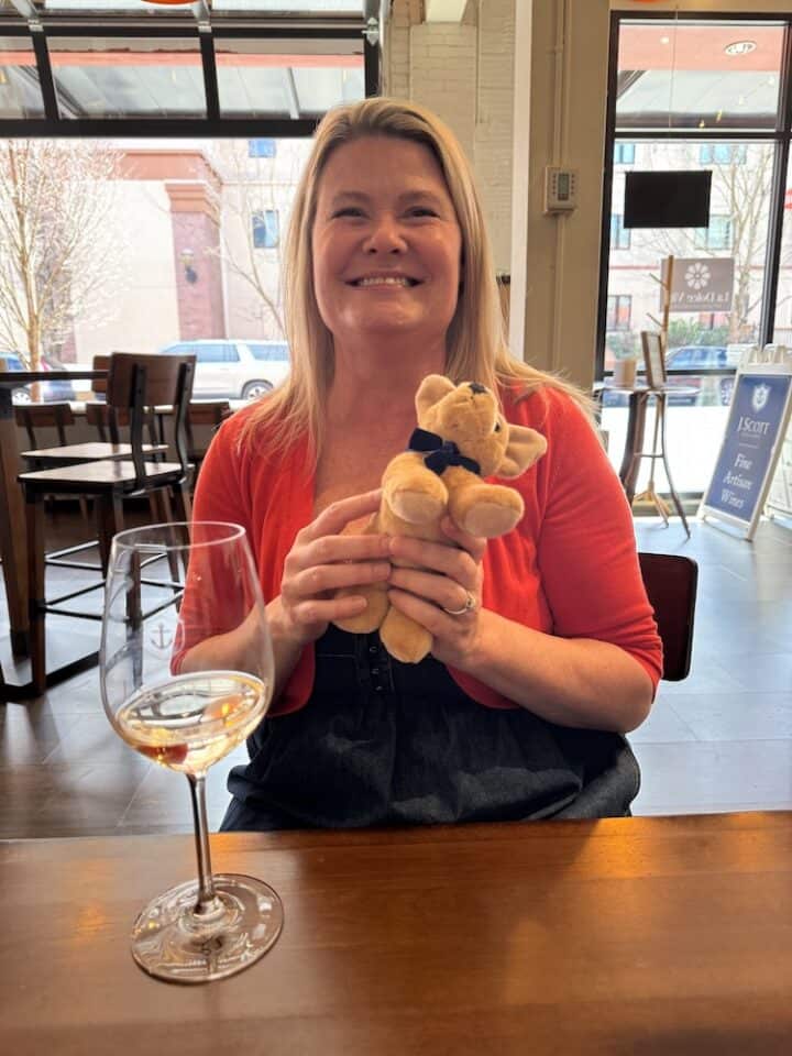 woman holding stuffed dog and enjoying a glass of wine